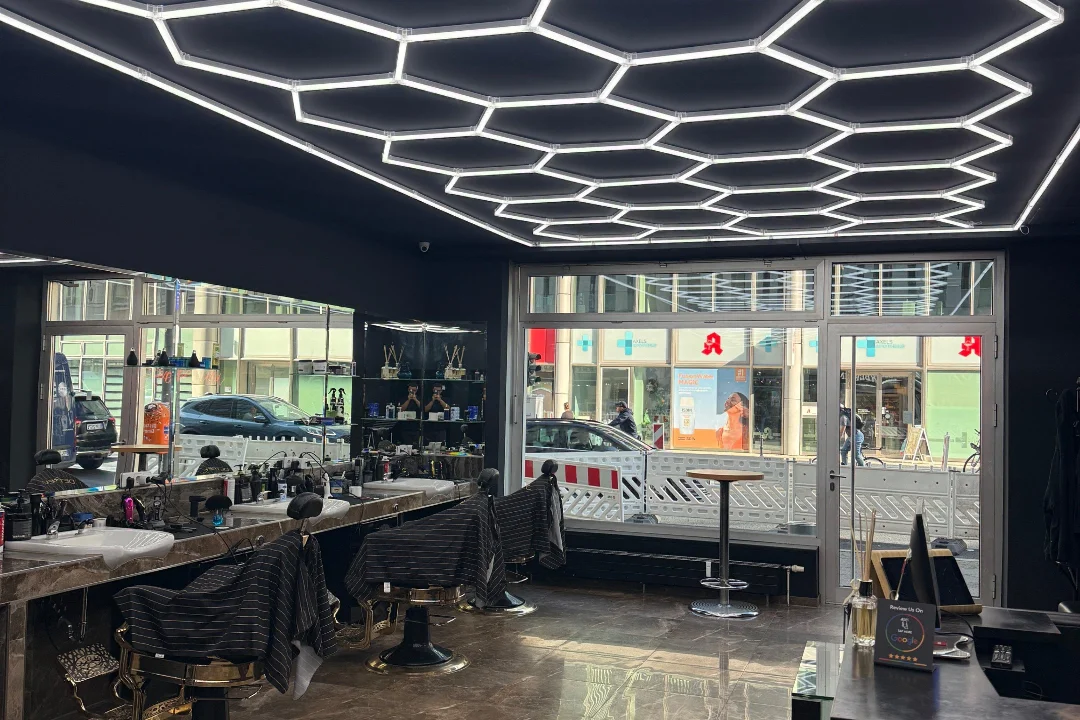 Barber-Chairs und Marmor-Konsolen unter der Hexagon-LED-Decke im Berberlin